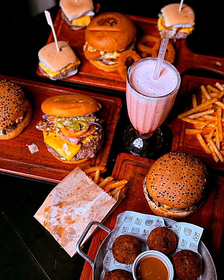 Post para Eita! Burger: Foto de produto: hambúrgueres, porções e milk-shake na mesma mesa.